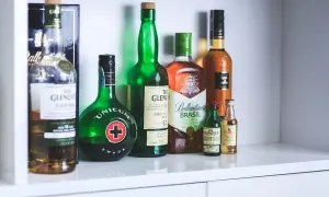 Rząd butelek z alkoholami, w tym Unicum i różne whisky, jakby zapomniane nalewki czekające na degustację.