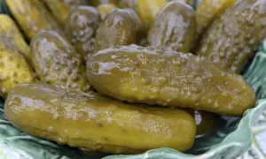Kosz pełen soczystych, zielonych ogórków kiszonych, które wyglądają na puste w środku, gotowe do chrupania.