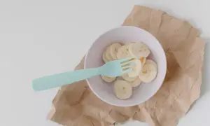 Miseczka z plasterkami banana i niebieskim widelcem. Czy królik może jeść banana? To pytanie nurtuje wielu właścicieli tych uroczych zwierząt.