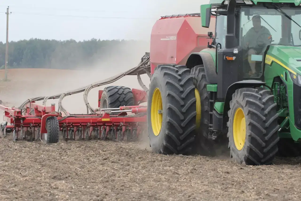 Zielony traktor z siewnikiem Horsch wykonuje uprawę pszenicy jarej krok po kroku, rozsiewając ziarno na przygotowanym polu.